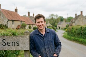 Homme souriant près du panneau Sens en campagne